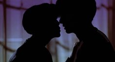 the silhouette of two people are facing each other