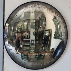 the reflection of a person in a mirror on a wall with furniture and mirrors behind it