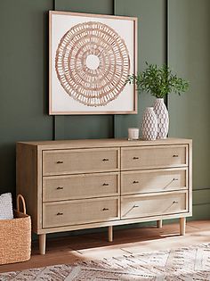 a living room scene with focus on the dresser and art hanging over it's top