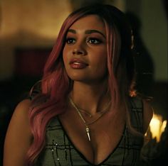 a woman with pink hair wearing a black and white dress in a dimly lit room