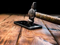 an old hammer is on top of a wooden table with a black object in the background