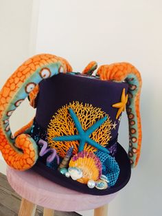 an orange and blue hat sitting on top of a wooden stool next to a starfish