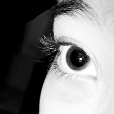 a close up of a person's eye with black and white hair in the background