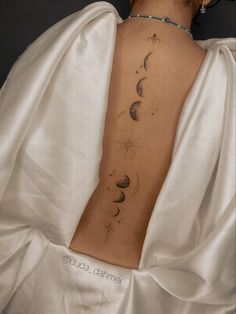 the back of a woman's body with phases and stars on it