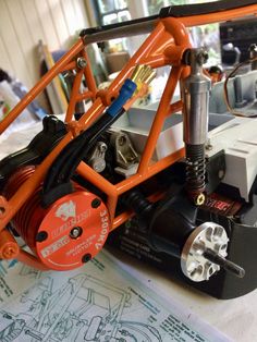 an orange and black toy car on top of a drawing board with wires attached to it