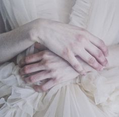 a woman in white dress holding her hands on top of another person's chest