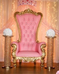 a pink and gold chair with flowers on it in front of a curtained backdrop