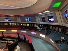 a control room with multiple monitors and lights on the walls, as well as several television screens