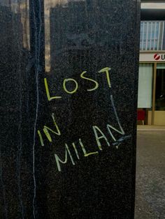 graffiti written on the side of a tall black object with words lost in italian and english