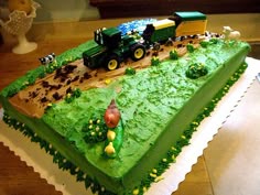 a cake that is shaped like a train on top of green frosting and decorated with farm animals