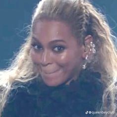 a close up of a person with long blonde hair and big earrings on her head