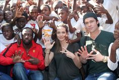 a group of people sitting next to each other with their hands up in the air
