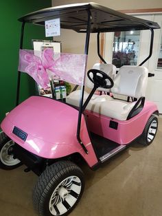 a pink golf cart with a bow on it