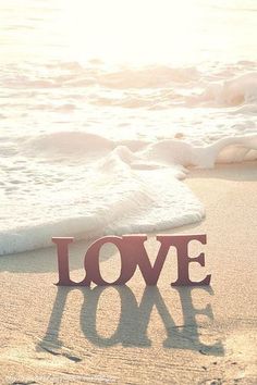 the word love is placed in the sand at the beach