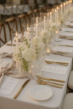 the table is set with white flowers and gold cutlery, candles and napkins