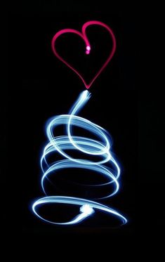 a heart shaped object is lit up in the dark with blue and red light streaks
