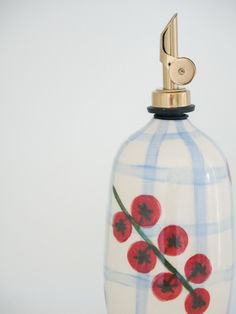 a white and blue vase with red flowers on it's side holding a golden metal clip