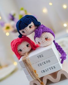 three small knitted dolls sitting on top of a wooden sign that says the cuckoo crafter