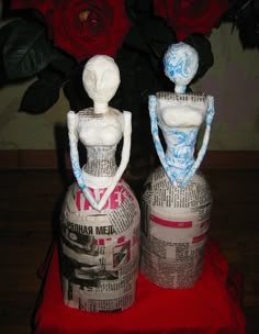 two vases made out of newspaper sit on a table