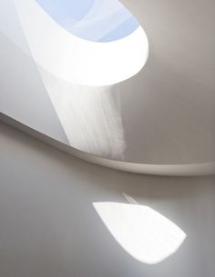 the sun shines through an arched window in a white room with curved walls and shadows on the wall