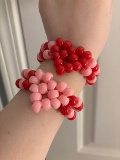 two red and pink bracelets on someone's arm