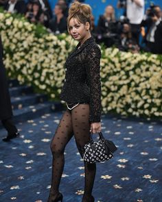 a woman in tights and heels walking on a blue carpet with flowers behind her