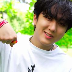 a young man with black hair wearing a white t - shirt and red bracelets