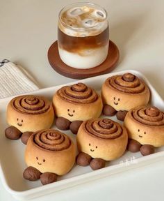 there are some rolls with faces on them and a cup of coffee in the background