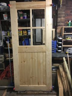 an unfinished wooden door in a garage with tools and supplies on the shelves behind it