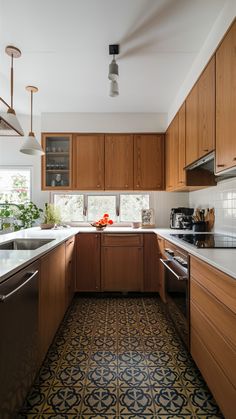 The fashion for teak kitchen designs reflects the mid-century modern style, brightening the ambiance with warmer colors and clean lines. The natural finish of teak is the right complement to white and gray color, it provides a sharp contrast. In addition, the design of the cabinets is mainly based on straight lines and geometric shapes. This style is combined with vintage decorations and is perfect for those whose hearts have been stolen by the retro look, but who want to give it a modern touch. Mid Century Kitchen Cabinet, Mid Century Rustic Kitchen, Mid Century Modern Kitchen Floor, Mid Century Wood Kitchen Cabinets, Mid Century Modern Kitchen Wood Cabinets, Teak Cabinets Mid Century, Teak Wood Kitchen Ideas, Teak Kitchen Ideas, Retro Kitchen Wood Cabinets