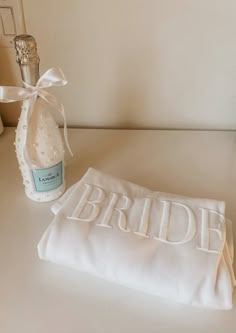 a white towel with the word bride written on it next to a bottle of perfume