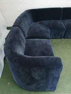 a large blue couch sitting on top of a green floor next to a white wall