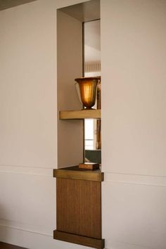 a shelf with a vase on top of it in a room that has white walls