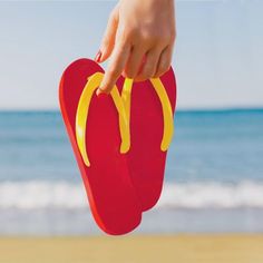 a pair of flip flops with a hot dog on them are held up by a person's hand