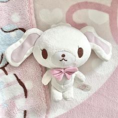 a white stuffed animal laying on top of a pink blanket