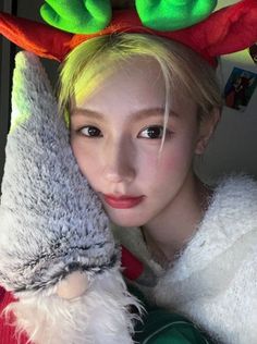 a girl with green hair and reindeer antlers on her head is posing for the camera