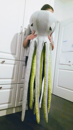 a woman holding an octopus stuffed animal in her arms while standing next to a white cabinet