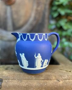 a blue and white vase sitting on top of a wooden table next to a statue