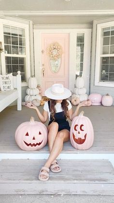 a woman sitting on the porch with two pumpkins