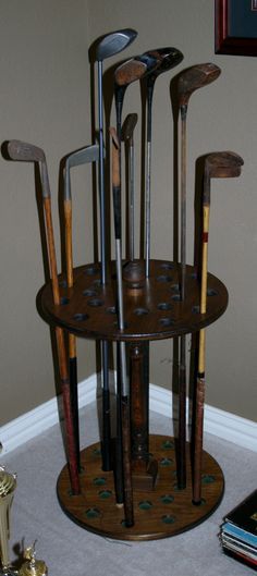 there are many different types of golf clubs in the holder on the floor next to books