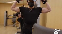 a man wearing a face mask and holding his hands behind his head in the gym