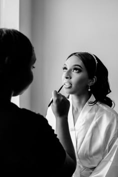 a woman is getting her make - up done in front of a mirror and looking into the distance