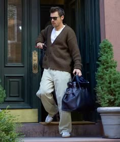 a man walking out of a door with a handbag