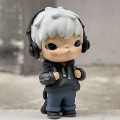 a small figurine with headphones on is standing next to a wall and looking at the camera