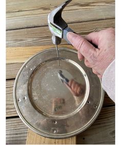 a person is holding a wrench over a metal pan with water in it on a wooden table