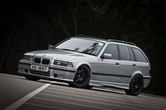 a silver car parked on the side of a road in front of trees and bushes