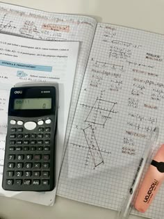 a calculator sitting on top of a notebook next to a pen and eraser