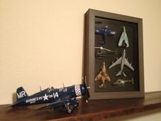 a toy airplane is sitting on top of a shelf next to a shadow box with other toys in it