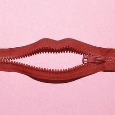 an open red zipper on a pink background