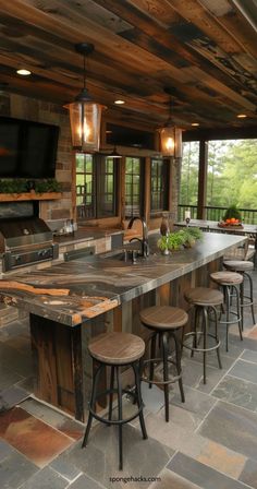 an outdoor kitchen with lots of counter space and stools around the bar area that is surrounded by stone flooring